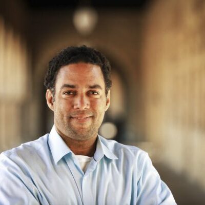 Professor Adam Banks Smiling in front of the Stanford Arches